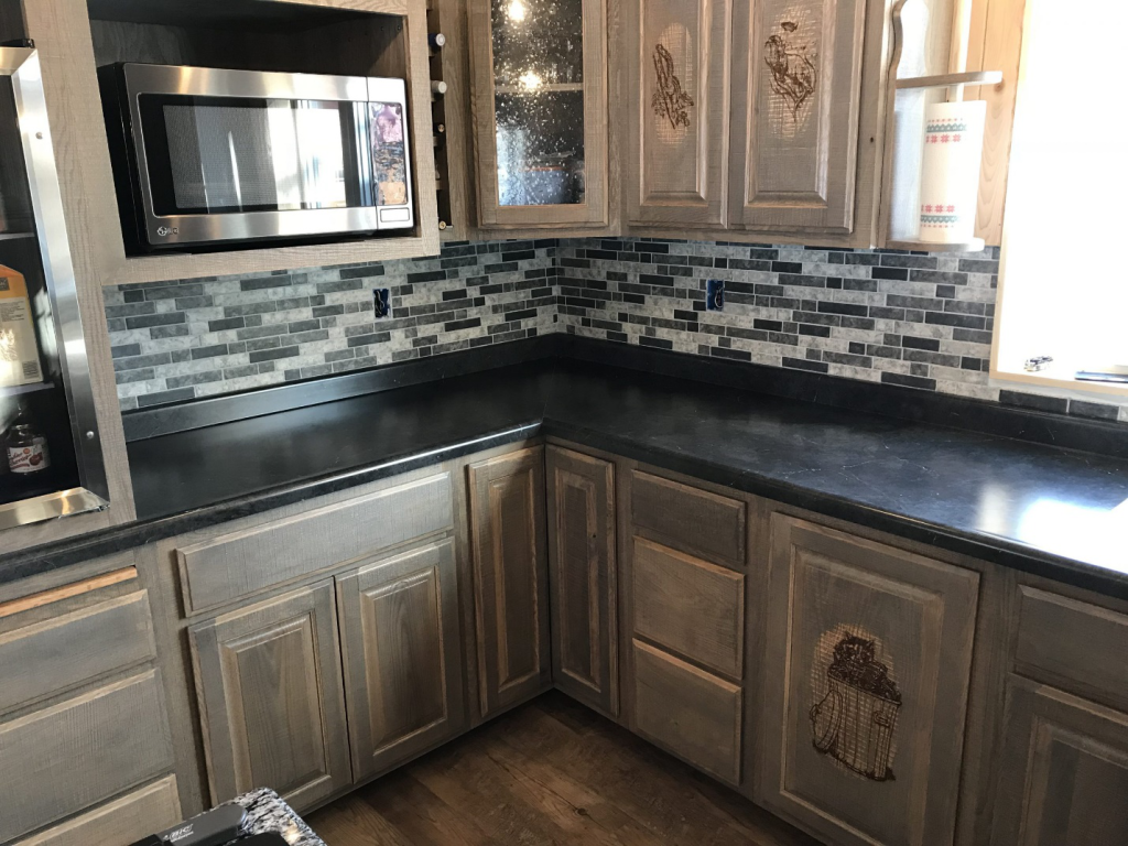 A kitchen with bright natural sunlight and grey cabinets, oven, etc. 