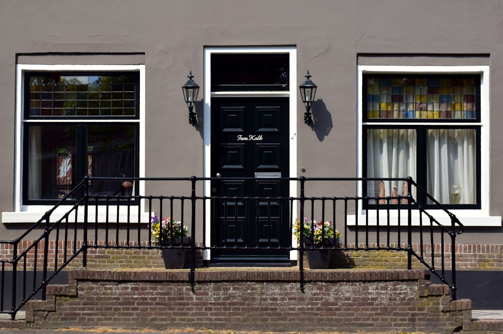 A building with a black door above the stairs and two large windows