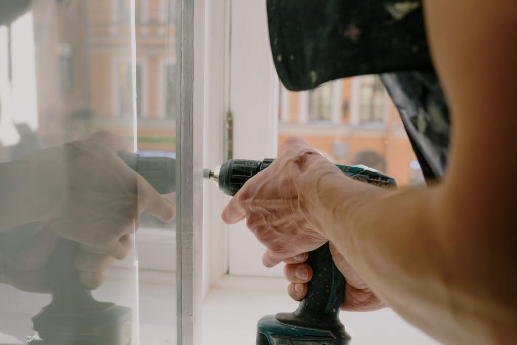 A general contractor in Rhinelander, WI, installing a new window using a drill machine.