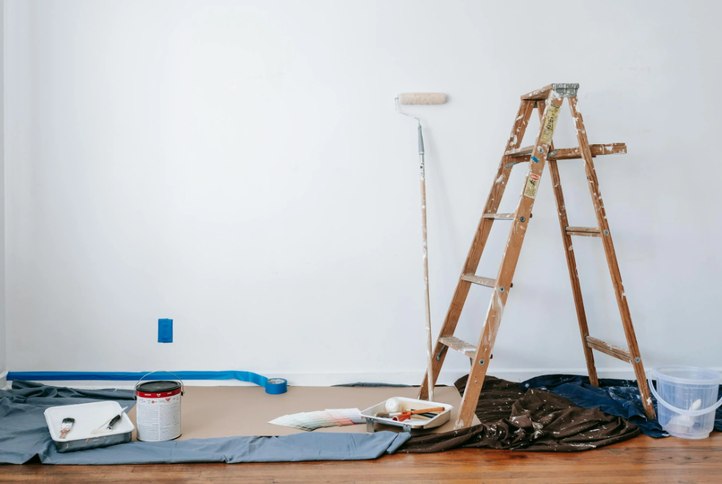 Home renovation set up with a wooden ladder, paint supplies, and a roller.