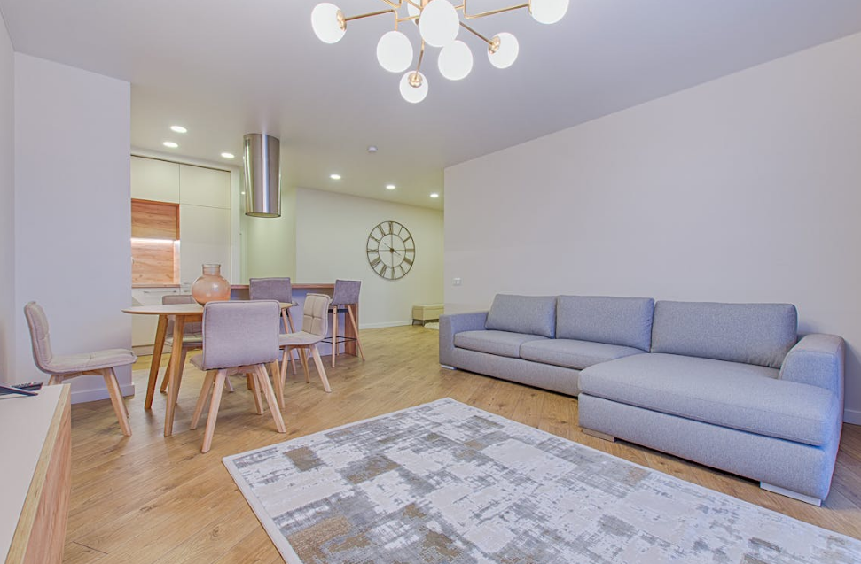 living room with a gray sectional sofa, dining area, and stylish lighting fixture.