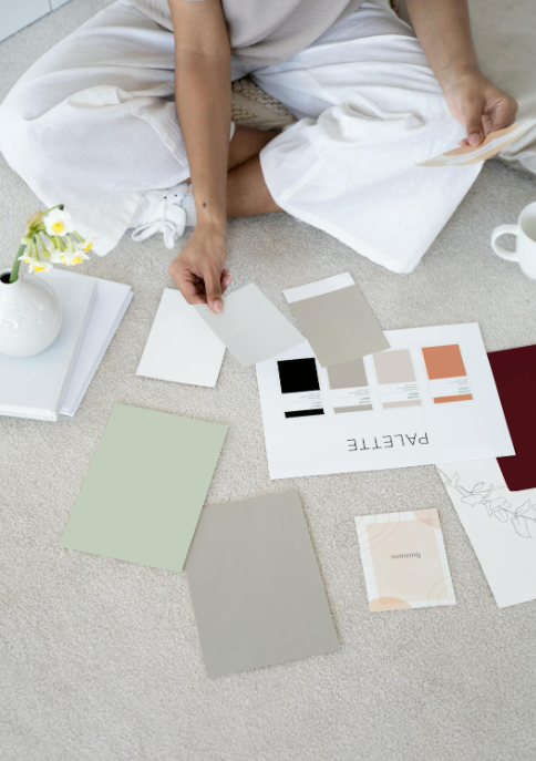 A person sitting on a carpet selecting color swatches and design palettes.